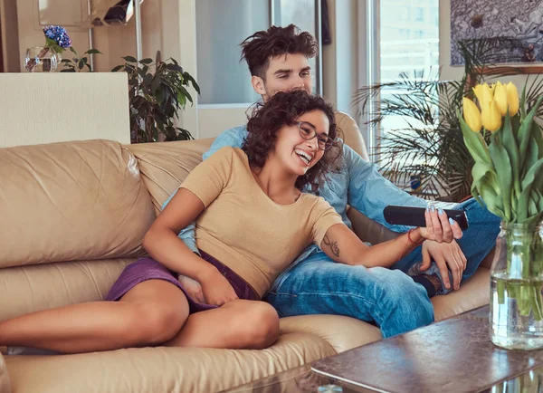 Νεαρό ζευγάρι αγκαλιά ενώ παρακολουθείτε τηλεόραση στο σπίτι. — Φωτογραφία Αρχείου