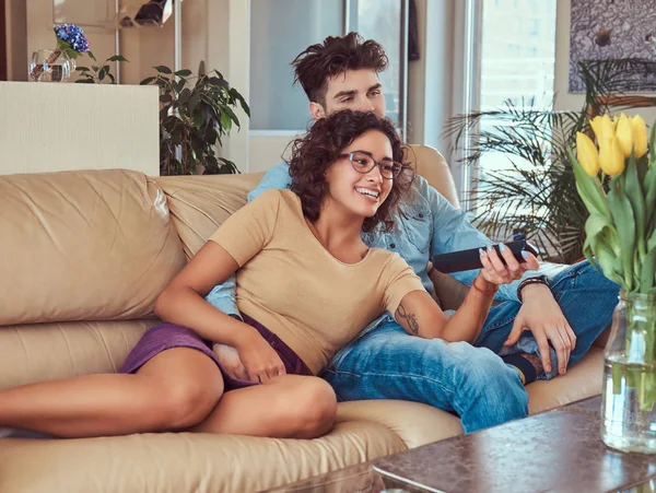 Jovem casal abraçando enquanto assiste TV em casa . — Fotografia de Stock