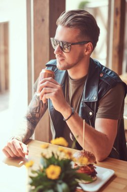 Yenilikçi bir şık saç ve sakal ile yol kenarına yerleştirilen bir kafede öğle yemeği için durdu bir masada oturur.