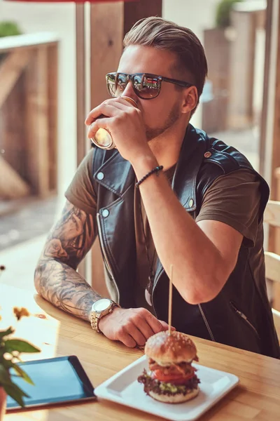 Yenilikçi bir şık saç ve sakal ile yol kenarına yerleştirilen bir kafede öğle yemeği için durdu bir masada oturur.