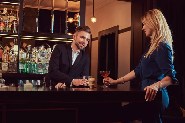 Casal elegante está passando a noite em um ambiente romântico, bebendo vinho no balcão do bar . — Fotografia de Stock