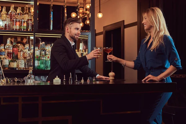 Casal elegante está passando a noite em um ambiente romântico, bebendo vinho no balcão do bar . — Fotografia de Stock