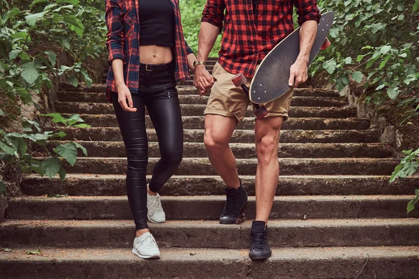 Genç hippi çift, elele, merdivenlerden inen bir parkta yürümek.