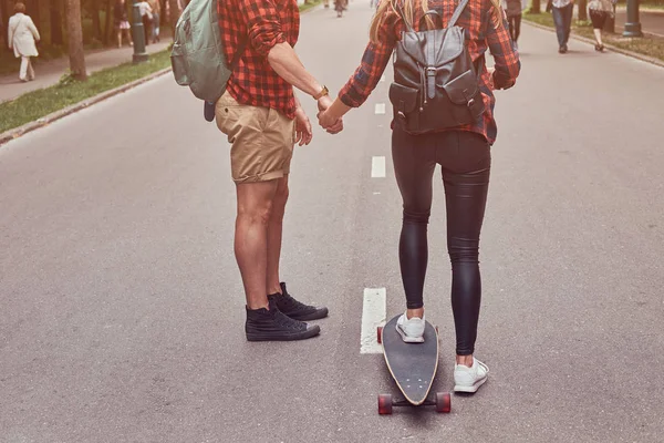 Unga hipster par. Killen lär hans flickvän att skateboard på gatan i en park. — Stockfoto