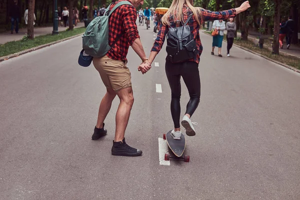 Молодая пара хипстеров. Парень учит свою девушку кататься на скейтборде в парке. . — стоковое фото