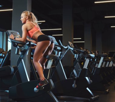 Modern fitness merkezinde bir egzersiz bisikleti günü spor eğitim genç güzel sarışın kadın.