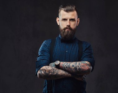 Mavi bir gömlek ve bir stüdyo çapraz kollarında ile ayakta pantolon askısı, yakışıklı bir eski moda hipster portresi.