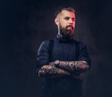 Mavi bir gömlek ve bir stüdyo çapraz kollarında ile ayakta pantolon askısı, yakışıklı bir eski moda hipster portresi.