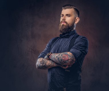 Mavi bir gömlek ve bir stüdyo çapraz kollarında ile ayakta pantolon askısı, yakışıklı bir eski moda hipster portresi.