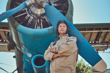 Yiğit yakışıklı pilot askeri uçak yakın Çapraz kollar ile ayakta tam uçuş viteste.