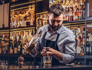 Bir gömlek ve önlük şık acımasız barmen, bir kokteyl bar counter arka plan yapar.