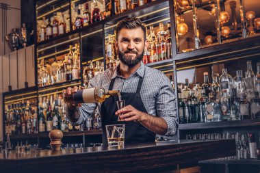 Bir gömlek ve önlük şık acımasız barmen, bir kokteyl bar counter arka plan yapar.