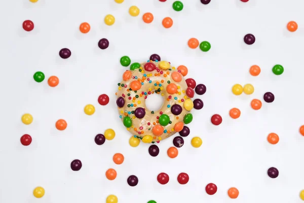 Appetizing golden donut sprinkled with colorful chocolate pellets. — Stock Photo, Image