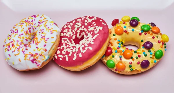 Three appetizing donuts lie on a pink ceramic plate. — Stock Photo, Image