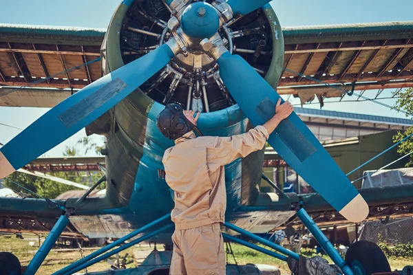 Piloto o mecánico en un tren de vuelo completo comprueba la hélice de su avión militar retro antes de un vuelo . — Foto de Stock