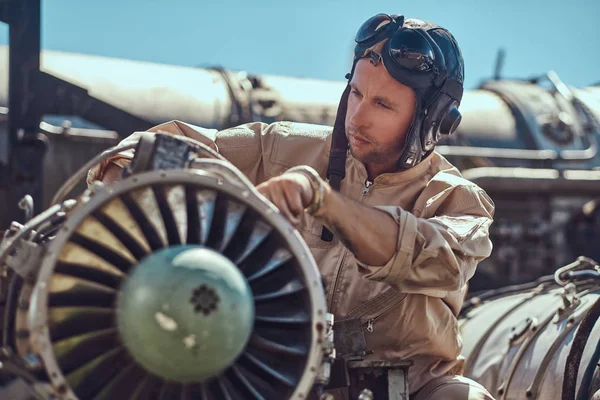 Retrato de um mecânico de capacete uniforme e voador, reparando a turbina de avião desmontada em um museu ao ar livre . — Fotografia de Stock