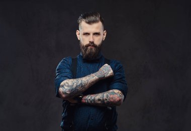 Mavi bir gömlek ve bir stüdyo çapraz kollarında ile ayakta pantolon askısı, yakışıklı bir eski moda hipster portresi.