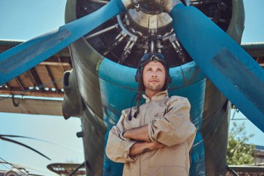 Yiğit yakışıklı pilot askeri uçak yakın Çapraz kollar ile ayakta tam uçuş viteste.