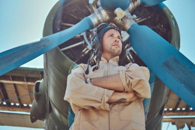 Yiğit yakışıklı pilot askeri uçak yakın Çapraz kollar ile ayakta tam uçuş viteste.