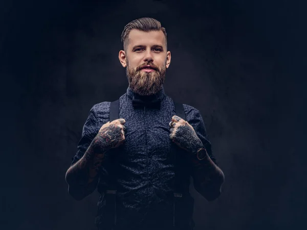 Smiling handsome old-fashioned hipster in a blue shirt and suspenders, posing in a studio. — Stock Photo, Image