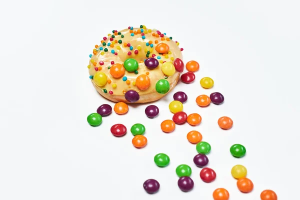 Appetizing golden donut sprinkled with colorful chocolate pellets. — Stock Photo, Image