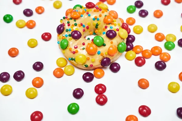 Smakelijk gouden donut besprenkeld met kleurrijke chocolade pellets. — Stockfoto