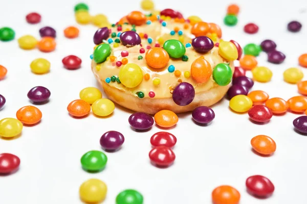 Appetizing golden donut sprinkled with colorful chocolate pellets. — Stock Photo, Image