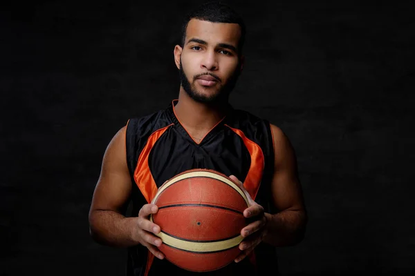 Giovane giocatore di basket afroamericano in abbigliamento sportivo isolato su sfondo scuro . — Foto Stock