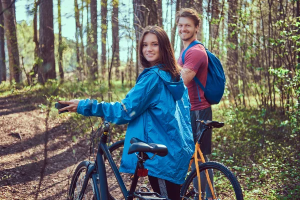 一群年轻的朋友徒步穿越森林与自行车在一个美丽的夏天天 — 图库照片