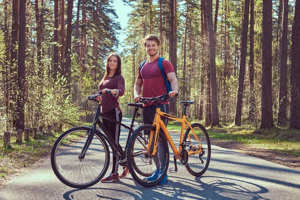 Grupo de jóvenes amigos caminando por el bosque con bicicletas en un hermoso día de verano — Foto de Stock