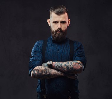 Mavi bir gömlek ve pantolon askısı ile ayakta, yakışıklı bir eski moda hipster portresi silah bir stüdyoda geçti. Karanlık bir arka plan üzerinde izole.