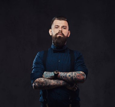 Mavi bir gömlek ve pantolon askısı ile ayakta, yakışıklı bir eski moda hipster portresi silah bir stüdyoda geçti. Karanlık bir arka plan üzerinde izole.