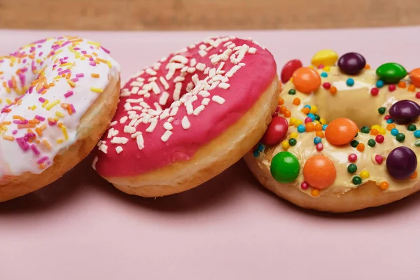 Three Appetizing Donuts Lie Pink Ceramic Plate Isolated Wooden Board — Stock Photo, Image