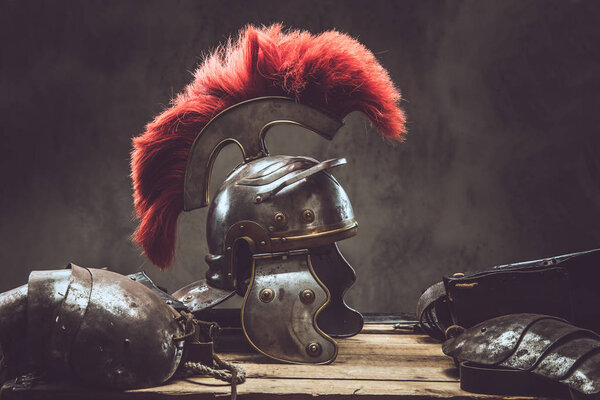 Complete combat equipment of the ancient Greek warrior lie on a box of wooden boards. Isolated on a dark background.