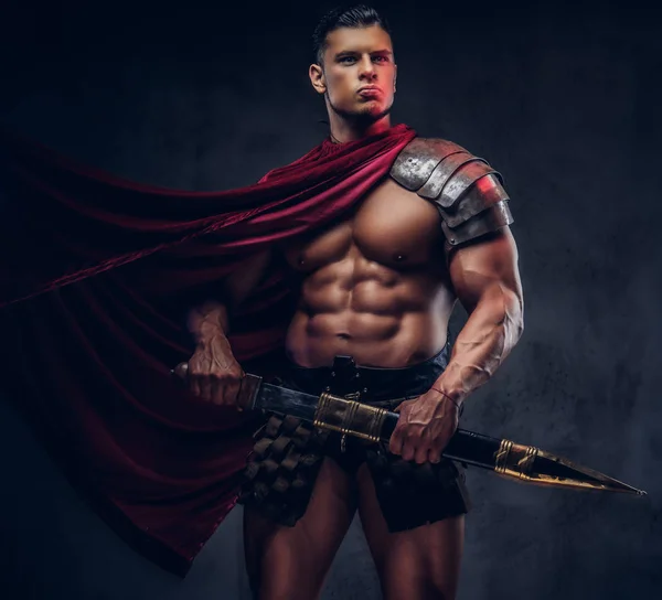 暗い背景にポーズの戦闘服で筋肉ボディを持つ残忍な古代ギリシャの戦士 — ストック写真