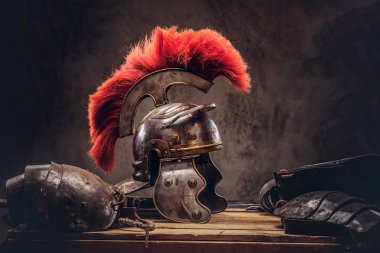 Complete combat equipment of the ancient Greek warrior lie on a box of wooden boards. Isolated on a dark background. clipart