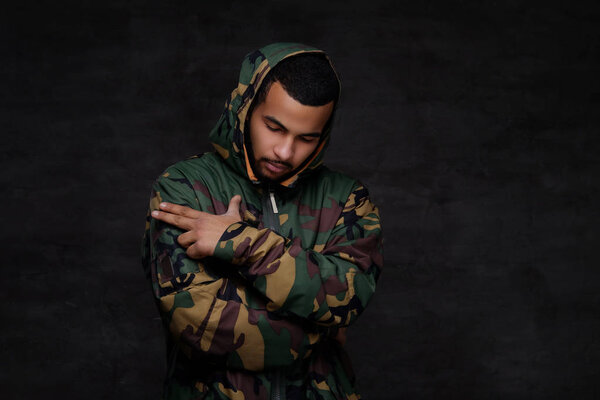 Handsome African-American guy wear military jacket. Isolated over dark background.