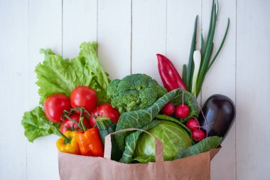 Beyaz ahşap tahtalar arka planda, üstten görünüm taze organik sebze. Sağlıklı gıda kavramı.