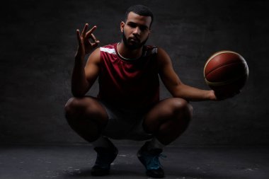 Bir top ile çömelme spor giyim, Afrikalı-Amerikalı basketbol oyuncusu. Koyu arka plan üzerinde izole. 