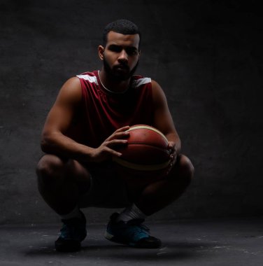 Bir top ile çömelme spor giyim, Afrikalı-Amerikalı basketbol oyuncusu. Koyu arka plan üzerinde izole. 