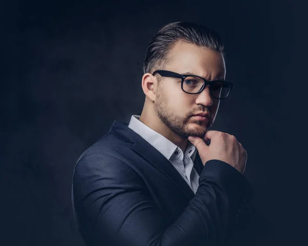 Gros plan portrait d'un homme d'affaires élégant et réfléchi avec un visage sérieux dans un élégant costume formel et des lunettes sur un fond sombre . — Photo