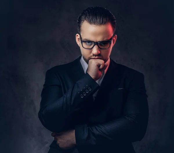 Gros plan portrait d'un homme d'affaires élégant et réfléchi avec un visage sérieux dans un élégant costume formel et des lunettes sur un fond sombre . — Photo