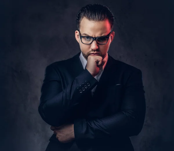 Nahaufnahme Porträt eines durchdachten, stilvollen Geschäftsmannes mit ernstem Gesicht in einem eleganten formalen Anzug und einer Brille auf dunklem Hintergrund. — Stockfoto