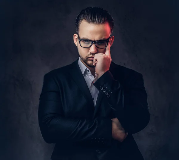 Retrato de cerca de un hombre de negocios con estilo reflexivo con cara seria en un elegante traje formal y gafas sobre un fondo oscuro . —  Fotos de Stock