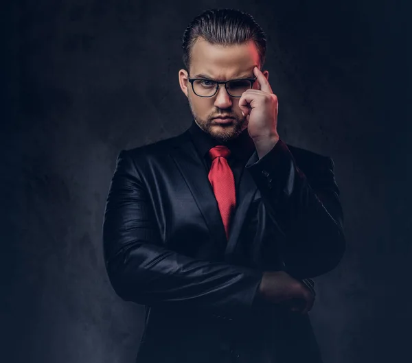 Portrait of a pensive stylish male in a black suit and red tie. — Stock Photo, Image