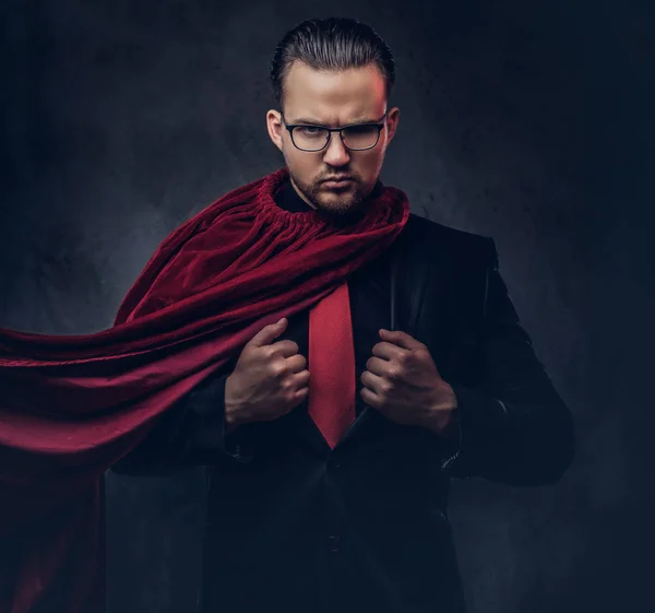 Ritratto di un genio supereroe in abito nero con cravatta rossa su sfondo scuro . — Foto Stock