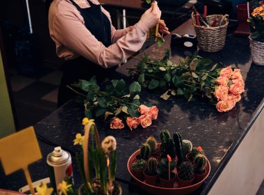 Kadın çiçekçi çiçekçi dükkanı kasada duran güzel çiçek kompozisyon yapmak üniforma.