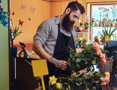 Sakal ve dövme elinde duran güzel çiçek kompozisyon çiçekçi dükkanı tezgahta yapma ile profesyonel erkek çiçekçi.