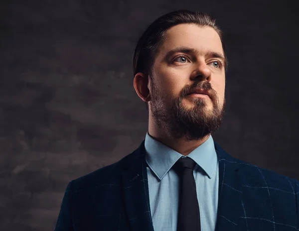 Close-up portrait of a handsome middle-aged man with beard and hairstyle dressed in an elegant formal suit. Isolated on a textured dark background in studio. — Stock Photo, Image