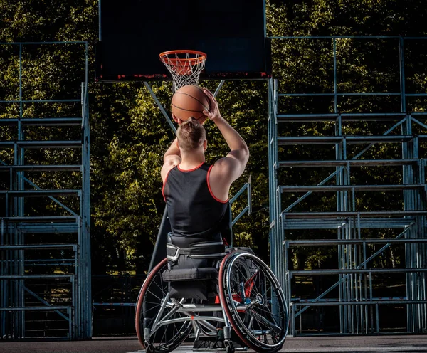 Krüppelnder Basketballer im Rollstuhl spielt auf offenem Spielfeld. — Stockfoto